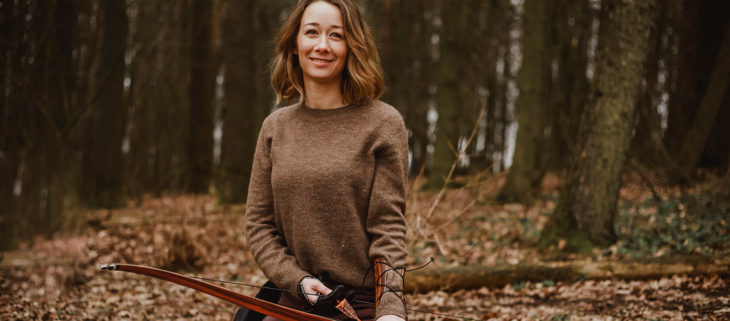 Eine Frau mit einem Bearpaw Bogen im Wald
